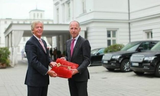 Peter J. Leitgeb (l.) händigt Tim Hansen, dem neuen Hoteldirektor des Grand Hotels Heiligendamm, symbolisch den Schlüssel für die Weiße Stadt am Meer aus.