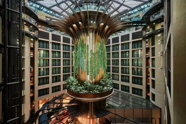 Radisson_Berlin_2025 Modernes Hotelatrium, grün bepflanzt, Deckenstruktur aus Holz und Glas, umgeben von mehrgeschossigen Zimmertrakten.