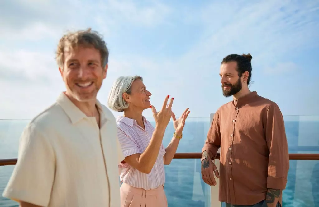 Drei plaudernde Personen an der Schiffsreling