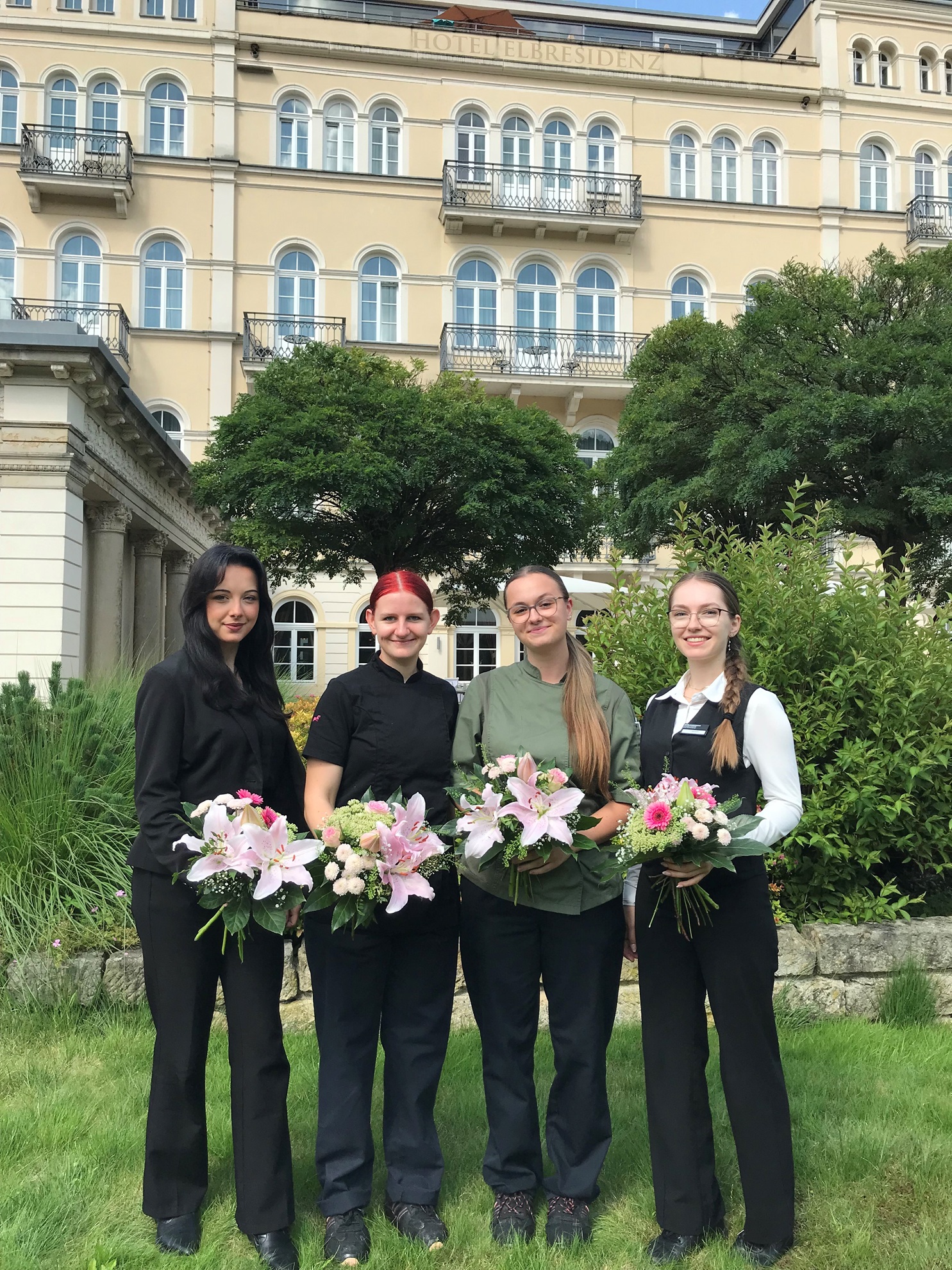 4 junge Damen mit Blumenstrauß vor Hotelgebäude