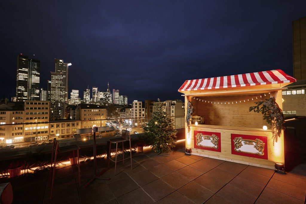 Nächtliche Atmosphäre auf Dachterrasse mit Weihnachtsbude und Blick in die beleuchtete Stadt