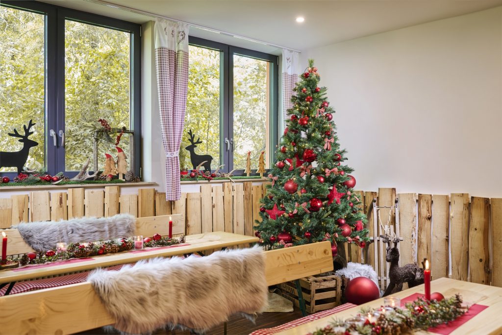 rustikale Einrichtung mit Bänken, Tischen, Fellen und Weihnachtsdekoration und Weihnachtsbaum