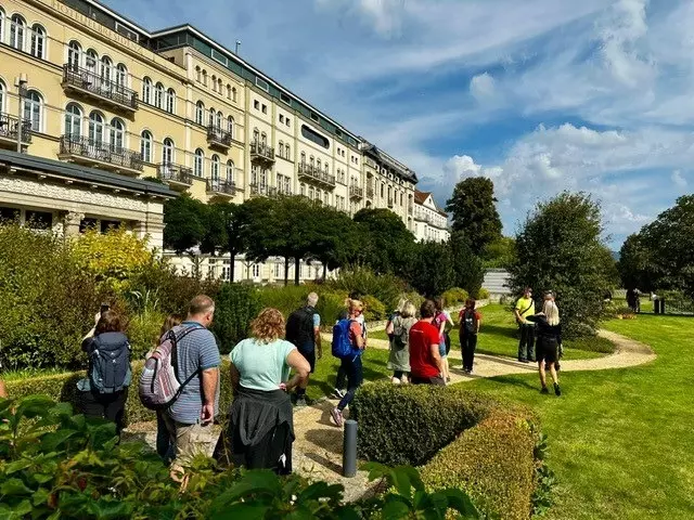 Bilder mit Menschen im Grünen vor Hotelgebäude