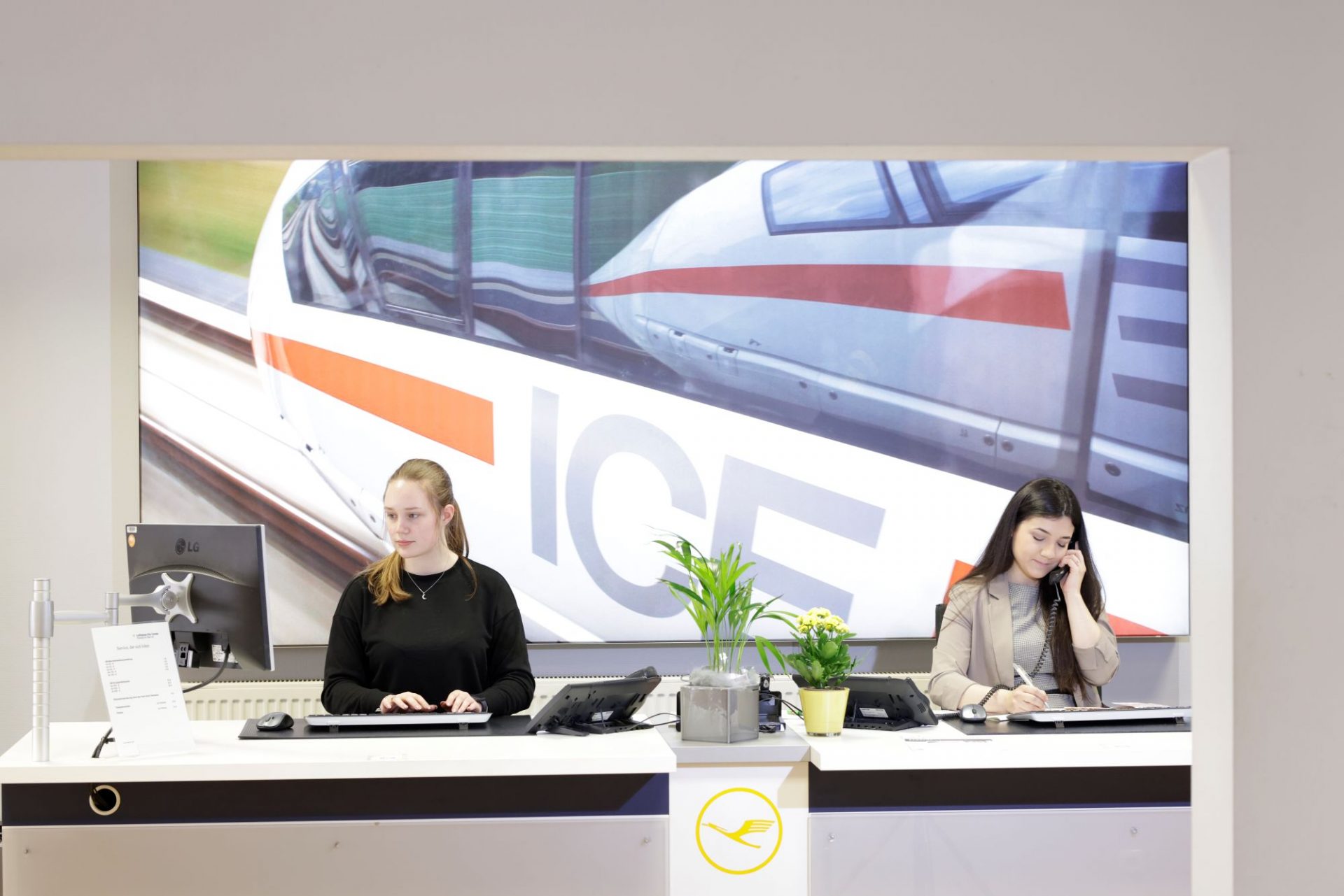 Zwei junge Frauen am Schreibtisch die am PC arbeiten und telefonieren