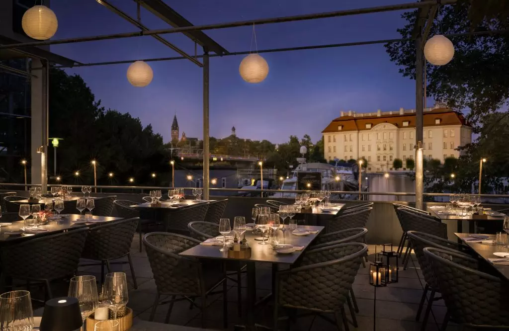 beleuchtete Terrasse in Berlin in Abendstimmung im Hintergrund Fluss und Boote