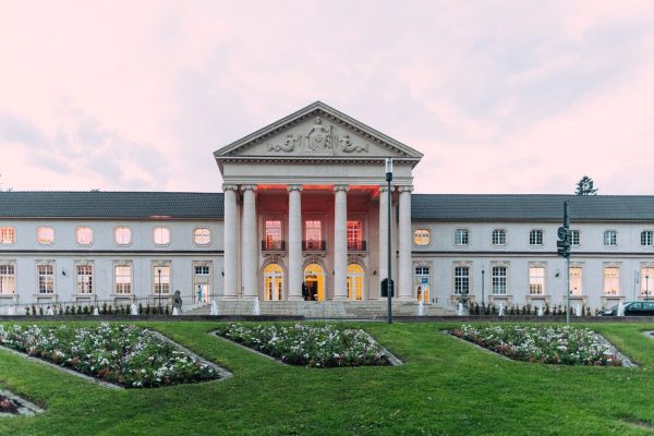 aachenax Blick auf historisches Gebäude, im Vordergrund Rasen mit Blumenbeeten